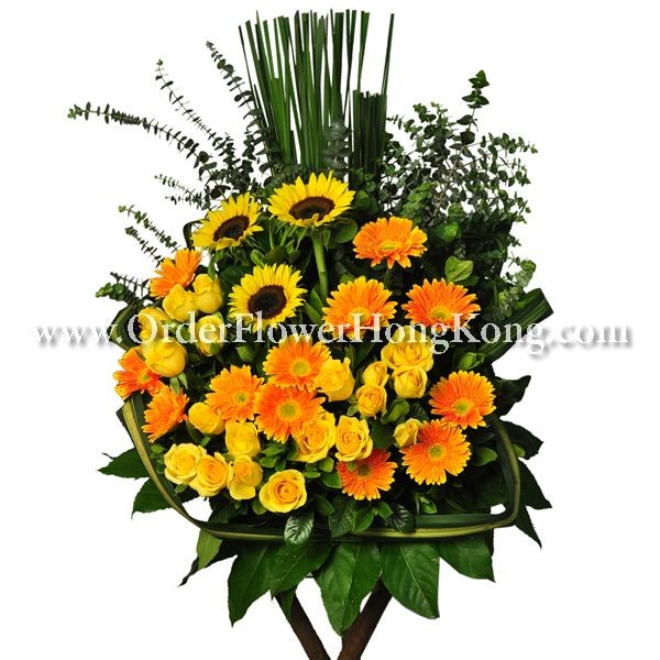 Vibrant floral arrangement with sunflowers, yellow roses, orange daisies, and green foliage.