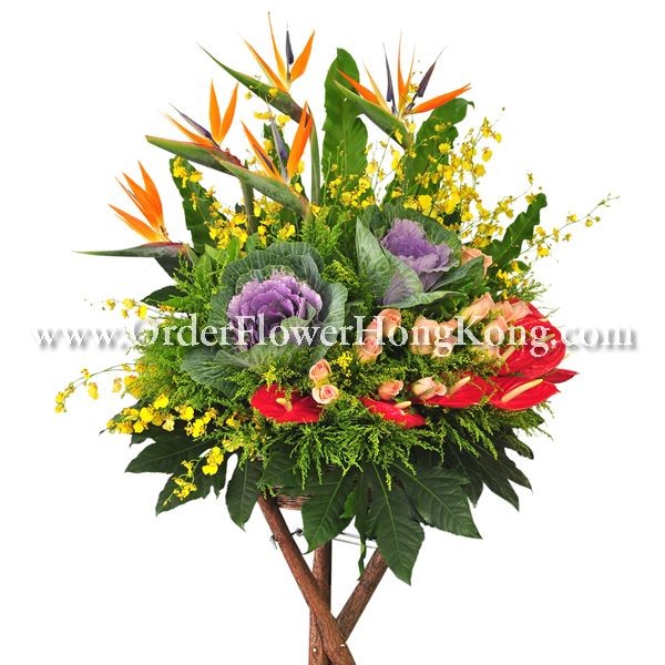 Vibrant flower arrangement with tropical blooms, roses, and greenery in a decorative display.
