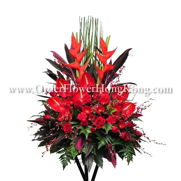 Vibrant floral arrangement with red anthuriums, roses, and tropical foliage.