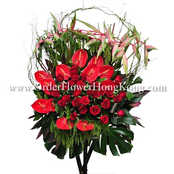 Elegant floral arrangement with red anthuriums, roses, greenery, and pink lilies.