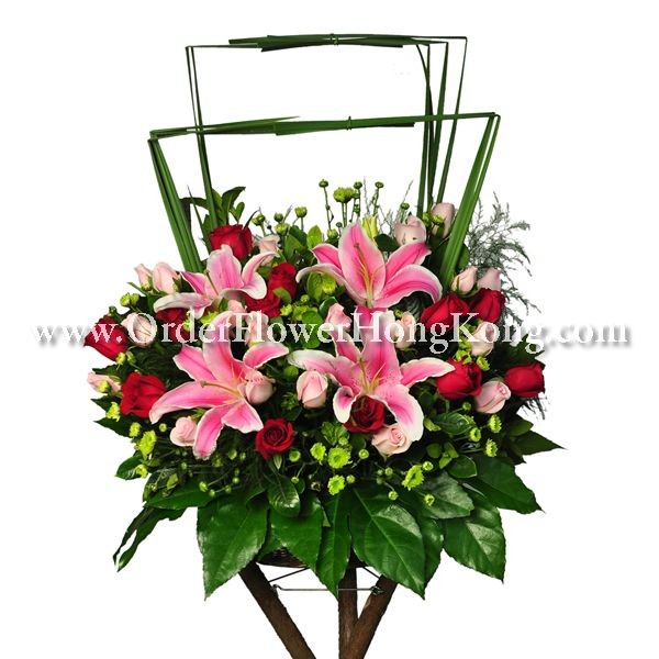 Elegant floral arrangement with pink lilies and red roses, accented by green leaves and delicate filler flowers.